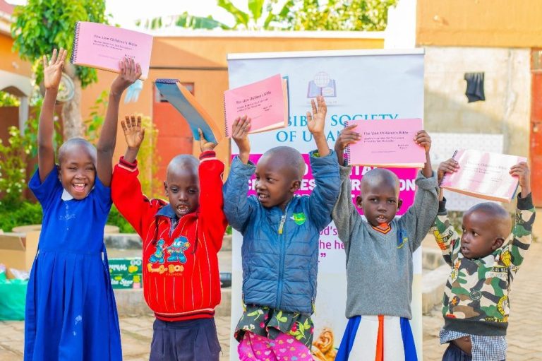 Ugandan children holding braille Lion Children's Bibles