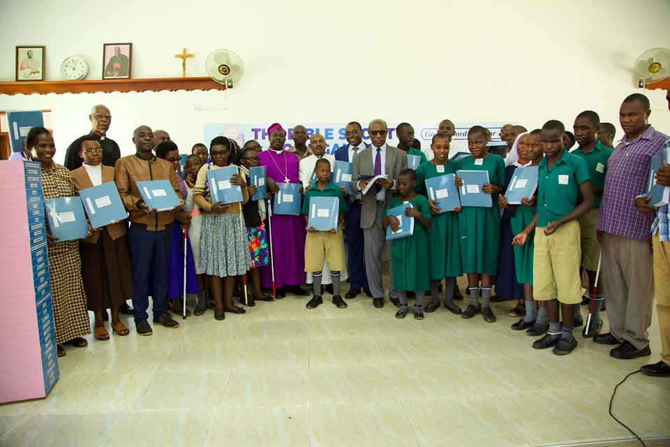 Group holding braille Runyankore/Rukiga Bible volumes