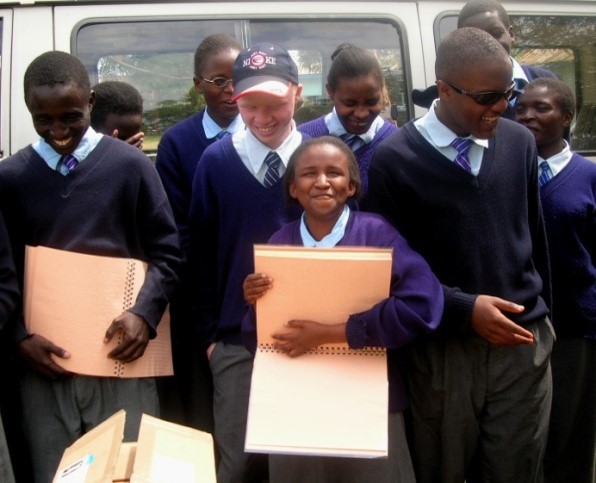 Visually impaired school children holding braille Bible volumes